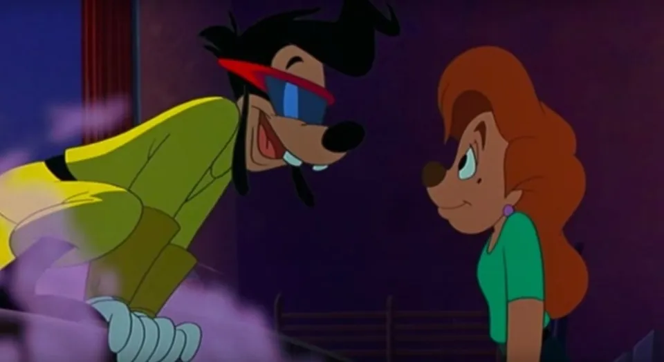 Max, wearing a yellow outfit and red-framed visor sunglasses, leans over a railing and grins at Roxanne, who smiles back in a green top