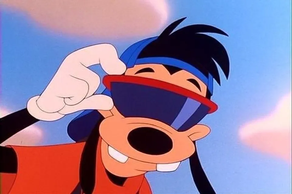 Max grins and adjusts red-rimmed visor sunglasses, wearing a backwards blue cap against a blue sky